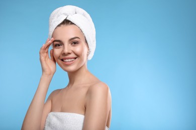 Happy young woman with towel on head against light blue background, space for text. Washing hair