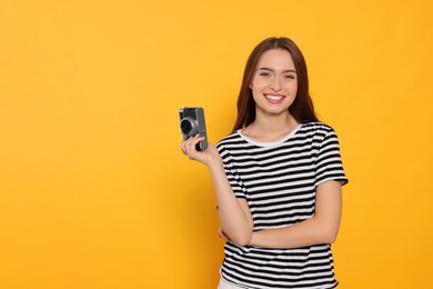 Young woman with camera on yellow background, space for text. Interesting hobby