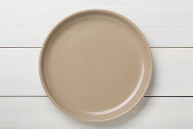 Empty ceramic plate on white wooden table, top view