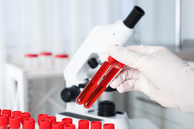 Scientist holding test tubes with blood samples in laboratory, closeup. Virus research