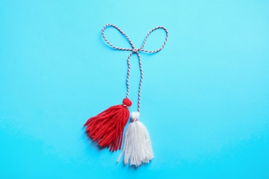 Photo of Traditional martisor on light blue background, top view. Beginning of spring celebration