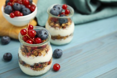 Delicious yogurt parfait with fresh berries on turquoise wooden table, closeup. Space for text