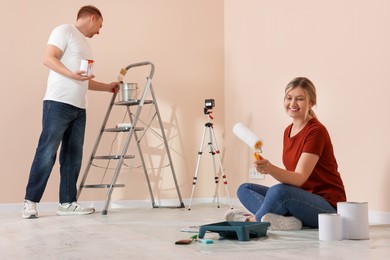 Happy couple with painting tools in apartment during repair
