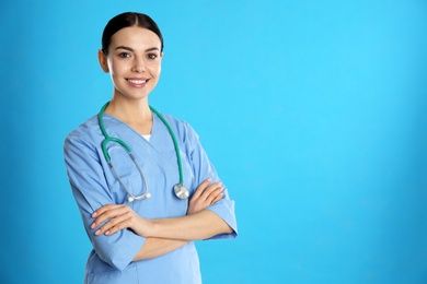 Portrait of young doctor with stethoscope on blue background. Space for text
