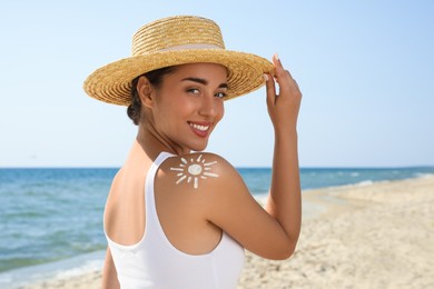 Photo of Beautiful young woman with sun protection cream on shoulder at beach