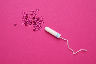 Tampon and sequins on pink background, flat lay. Menstrual hygiene product
