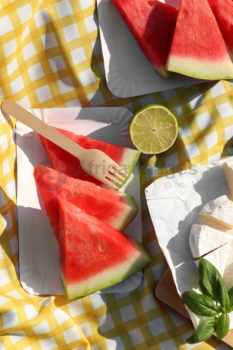 Delicious watermelon, cheese and lime on picnic blanket, flat lay