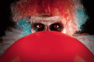 Photo of Terrifying clown with red air balloon, closeup. Halloween party costume