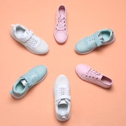 Flat lay composition with different stylish sports shoes on pale coral background