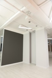 Blurred view of empty office room with color walls and modern lights on ceiling. Interior design
