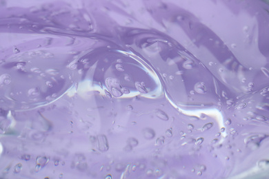Pure transparent cosmetic gel on lilac background, closeup