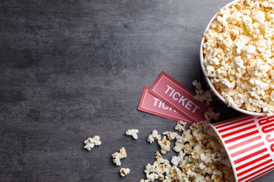 Popcorn and tickets on grey stone table, flat lay with space for text. Cinema snack