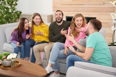 Group of friends telling jokes and laughing in living room