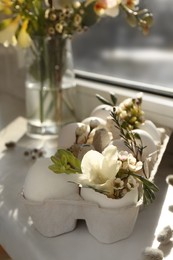 Photo of Festive composition with eggs and floral decor on windowsill indoors. Happy Easter