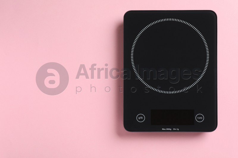Modern digital kitchen scale on pink background, top view. Space for text