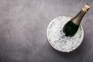 Champagne in metal bucket with ice on grey table, top view. Space for text