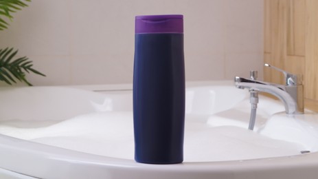 Purple bottle of bubble bath on tub indoors