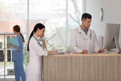 Receptionist and doctor working at countertop in hospital