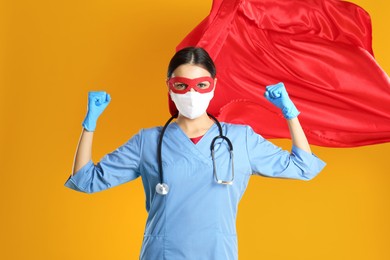 Doctor dressed as superhero posing on yellow background. Concept of medical workers fighting with COVID-19