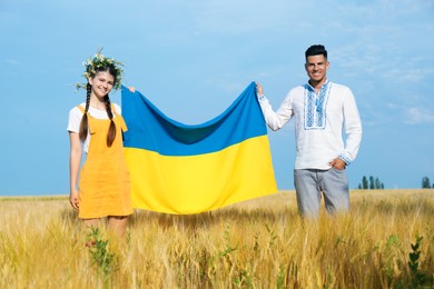 Friends holding national flag of Ukraine in field