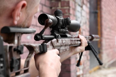 Soldier holding modern powerful sniper rifle with telescopic sight outdoors, closeup