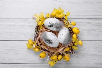 Photo of Festively decorated Easter eggs on white wooden table, top view