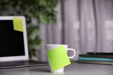 Cup with blank sticky note on white wooden table indoors. Space for text