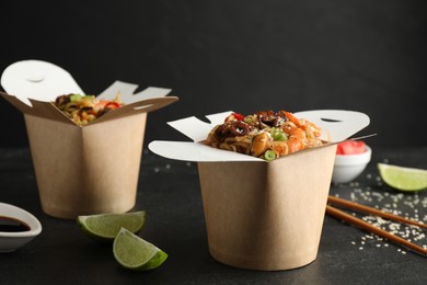 Boxes of wok noodles with seafood on black table