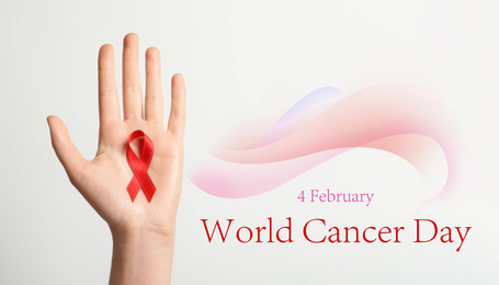 Woman holding red ribbon on white background, top view. World Cancer Day