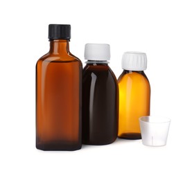 Photo of Bottles of syrups with measuring cup on white background. Cough and cold medicine