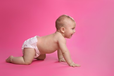 Cute baby in dry soft diaper crawling on pink background