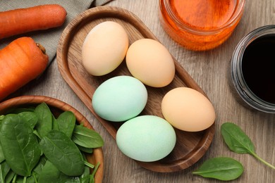 Photo of Painted Easter eggs with natural organic dyes (spinach and carrot) on wooden table, flat lay