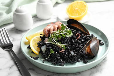Delicious black risotto with seafood on white marble table