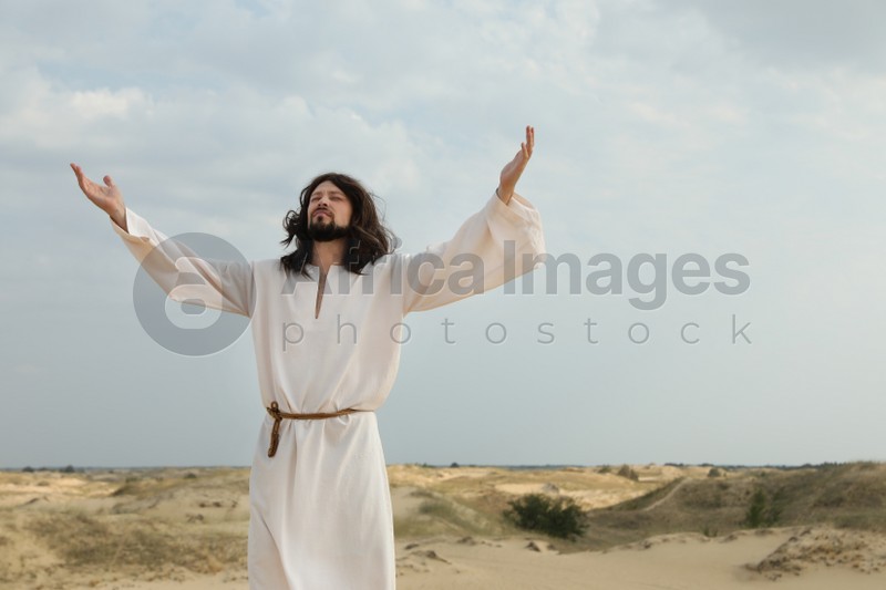 Jesus Christ raising hands in desert on sunny day