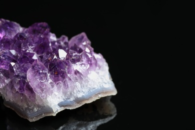Photo of Beautiful purple amethyst gemstone on black background, closeup. Space for text