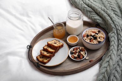Tray with tasty breakfast on bed in morning