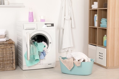 Washing machine with dirty clothes and towels in laundry room
