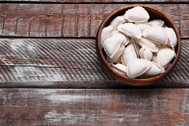 Photo of Raw dumplings (varenyky) on wooden table, top view. Space for text