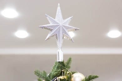 Photo of Silver star topper on Christmas tree indoors