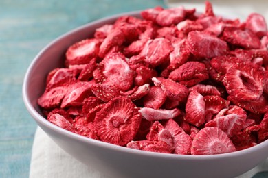 Bowl with dried strawberries on light blue table, closeup