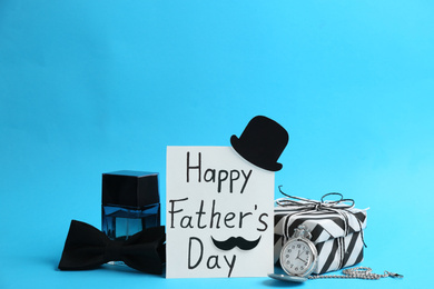 Card with phrase HAPPY FATHER'S DAY and male accessories on light blue background