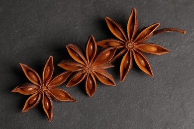 Photo of Aromatic anise stars on black table, flat lay