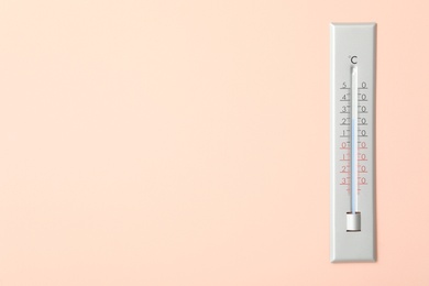 Weather thermometer on pink wall. Space for text