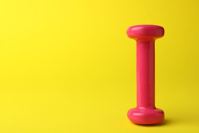Stylish dumbbell on yellow background, space for text