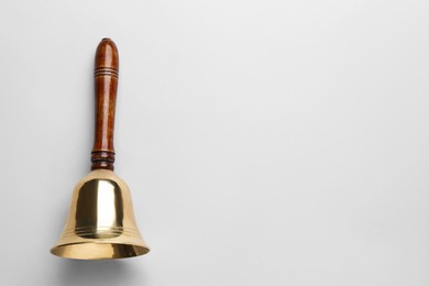 Golden school bell with wooden handle on grey background, top view. Space for text