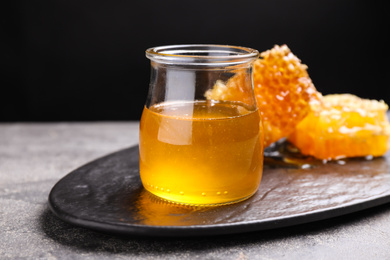 Photo of Tasty aromatic honey and combs on grey table