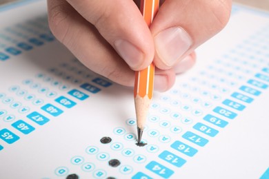 Photo of Student filling answer sheet at table, closeup. Passing exam