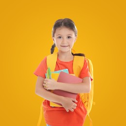 Cute child with school stationery on yellow background