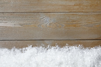 Snow and space for text on wooden background, top view. Christmas time