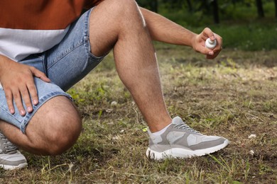 Man applying insect repellent on leg in park, closeup. Tick bites prevention